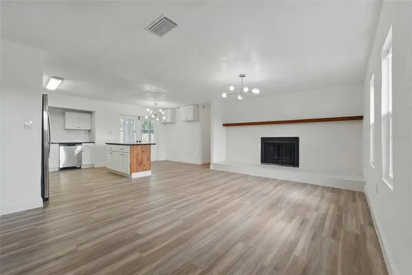a kitchen with stainless steel appliances a stove a sink dishwasher a refrigerator and white cabinets with wooden floor
