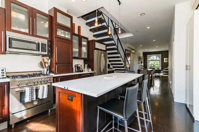 a open kitchen with stainless steel appliances granite countertop a stove and a dining table