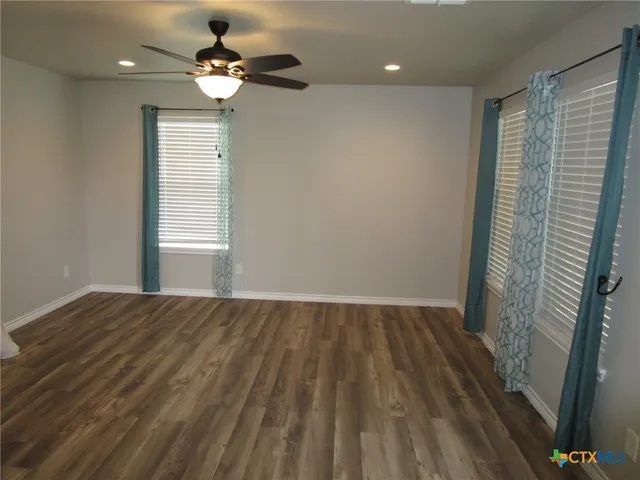 a view of empty room with wooden floor and fan