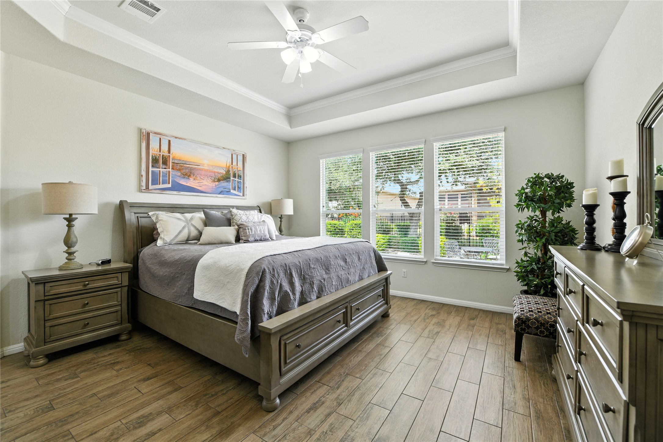 107 Calhoun Lane Georgetown, TX 78633 - Photo 16 of 36 Primary bedroom featuring a tray ceiling, wood look tile floors and plenty of natural light
