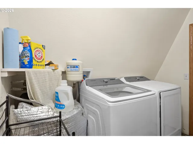 a utility room with dryer washer and a view of living room
