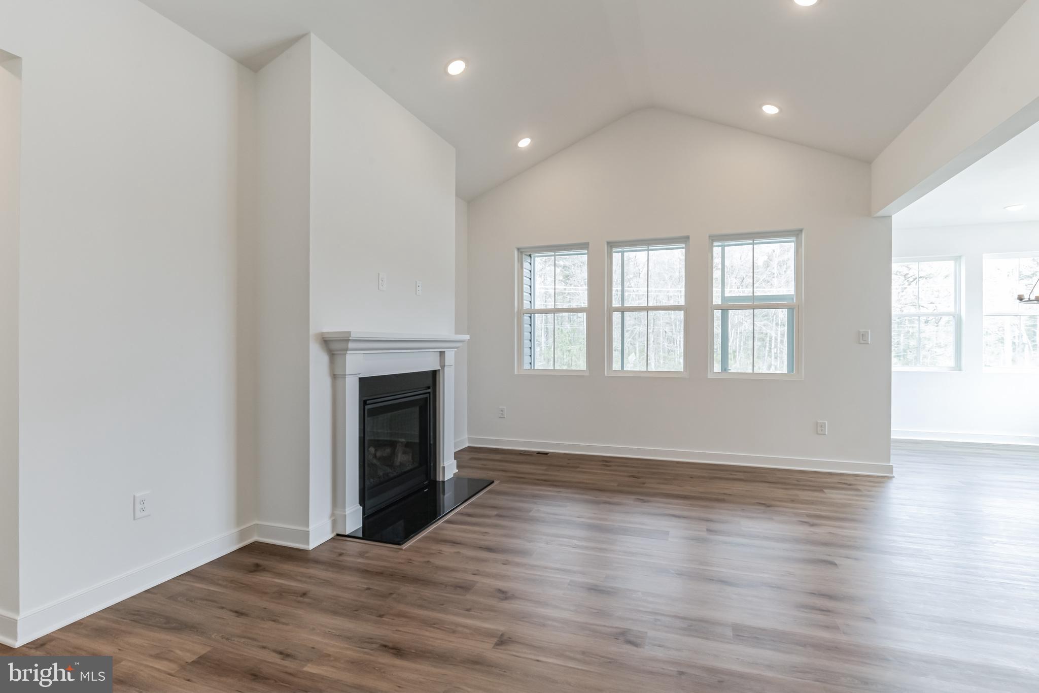 36449 Maple Ridge Lane Georgetown, DE 19947 - Photo 14 of 39 an empty room with wooden floor fireplace and windows