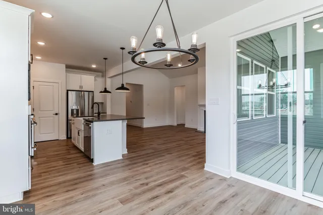a view of kitchen and empty room with wooden floor
