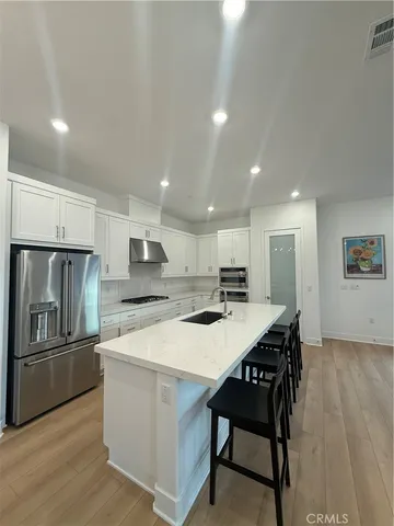 a kitchen with stainless steel appliances granite countertop a refrigerator a stove a sink a dining table and chairs