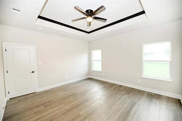 an empty room with wooden floor fan and windows