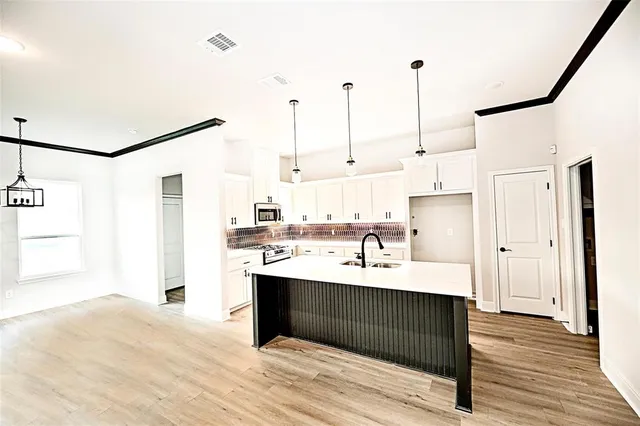 a kitchen with kitchen island a sink appliances and cabinets