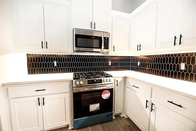 a kitchen with a stove and white cabinets