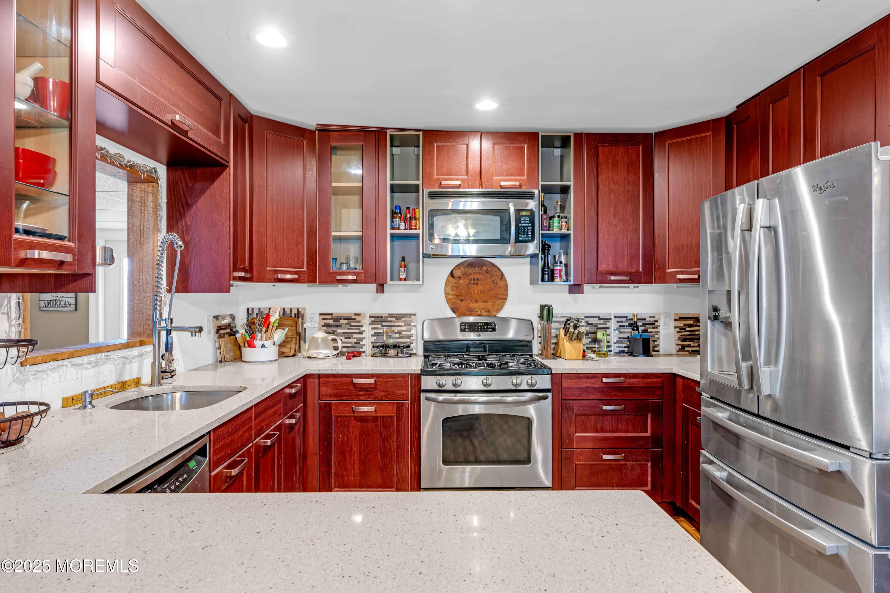 64 Roland Street Keansburg, NJ 07734 - Photo 10 of 38 a kitchen with stainless steel appliances granite countertop a stove top oven a refrigerator and a sink with wooden cabinets
