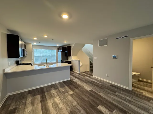 a kitchen with kitchen island granite countertop a sink and a stove top oven with wooden floor
