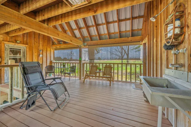 a backyard of a house with lawn chairs plants and large tree
