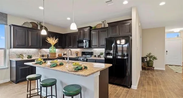 a kitchen with a sink a refrigerator and chairs