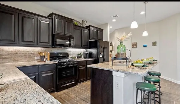 a kitchen with kitchen island granite countertop a sink cabinets and stainless steel appliances