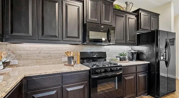 a kitchen with granite countertop a stove sink and refrigerator
