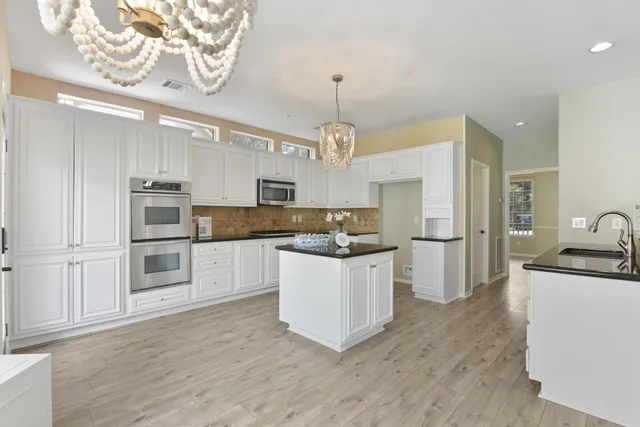 a dining room with wooden floor a chandelier a glass table and chairs