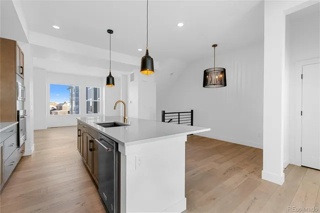 a kitchen with stainless steel appliances kitchen island a hardwood floor and a sink