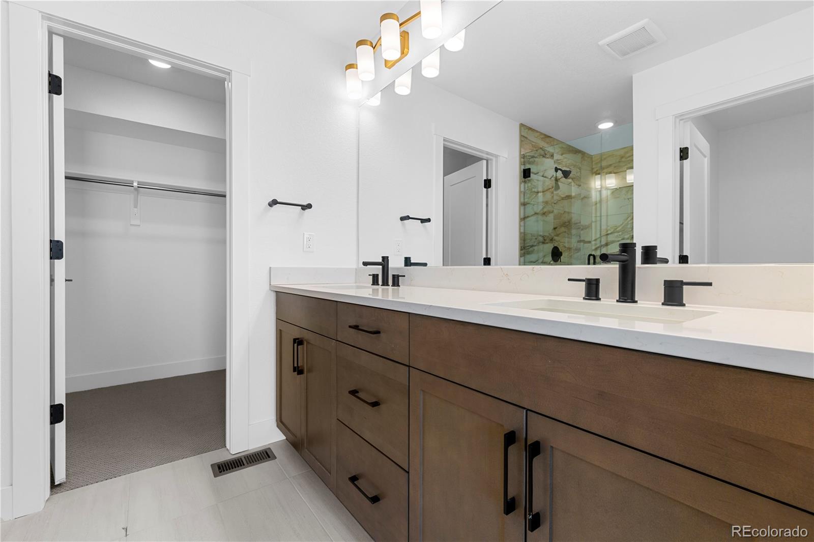 14241 Currant Street Broomfield, CO 80020 - Photo 22 of 25 a bathroom with a double vanity sink a mirror and a shower