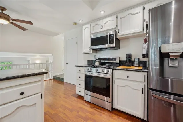 a kitchen with stainless steel appliances white cabinets a sink and a stove