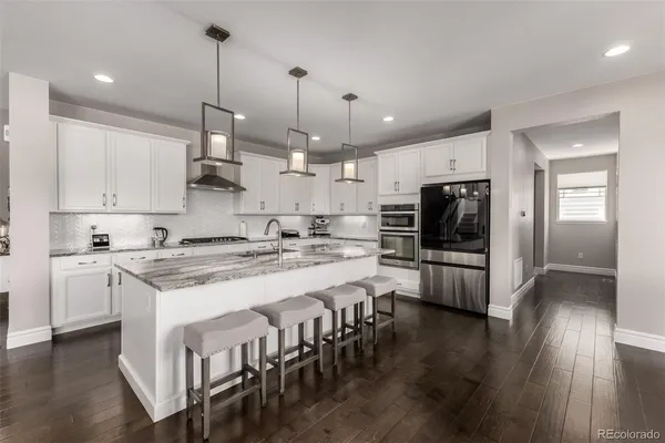 a kitchen with stainless steel appliances granite countertop a stove a sink a kitchen island with a dining table and chairs