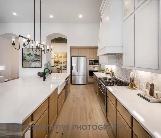 a kitchen with stainless steel appliances a sink a stove top oven a counter space and cabinets