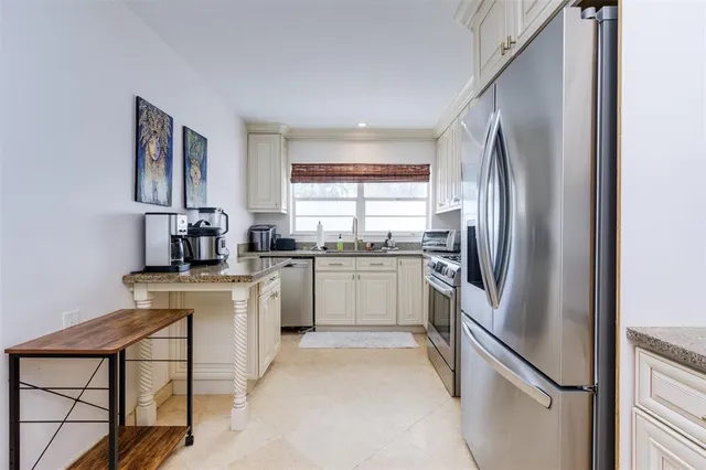 a kitchen with granite countertop white cabinets and stainless steel appliances