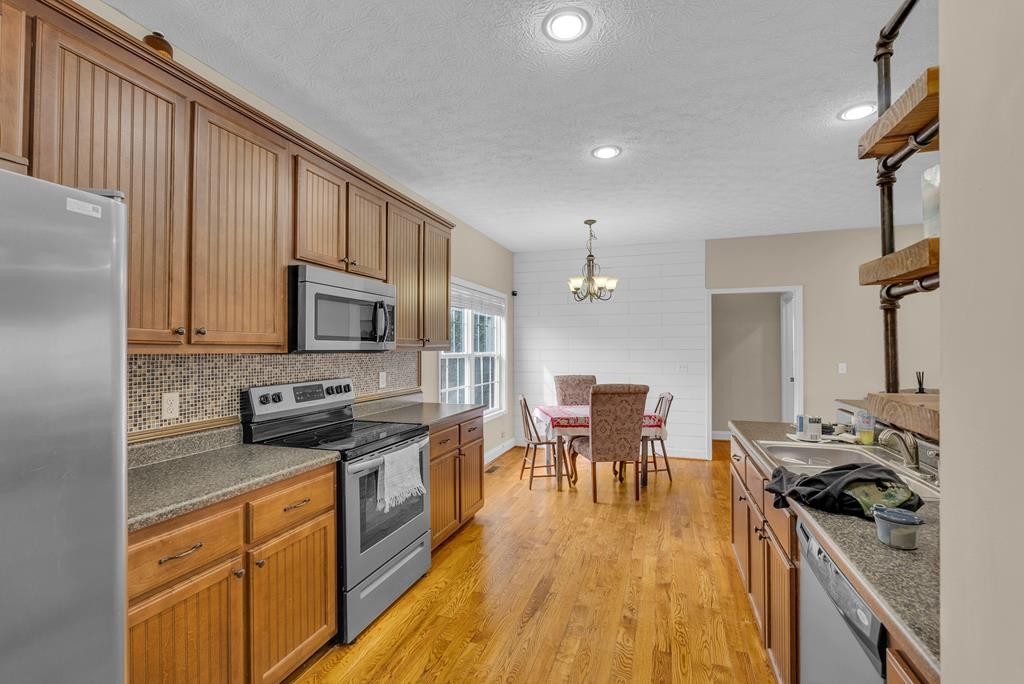 821 Honeysuckle Lane Sparta, TN 38583 - Photo 12 of 25 a kitchen with stainless steel appliances granite countertop a stove top oven a sink a dining table and chairs with wooden floor