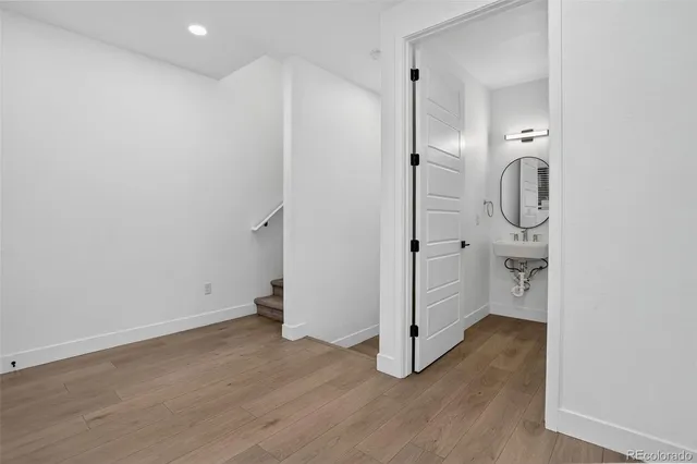 a view of an empty room with wooden floor and a hallway