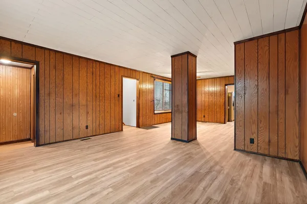 an empty room with wooden floor and windows