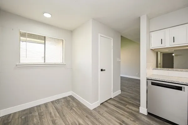 an empty room with wooden floor cabinet and windows