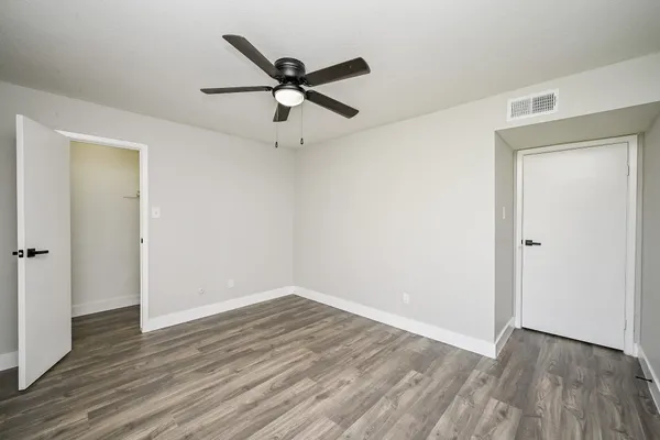 an empty room with wooden floor and a ceiling fan