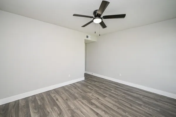 a view of a room with wooden floor and a ceiling fan