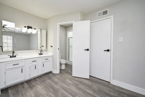 a spacious bathroom with a double vanity sink a mirror and a shower
