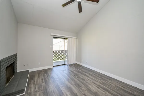 an empty room with wooden floor fireplace and windows