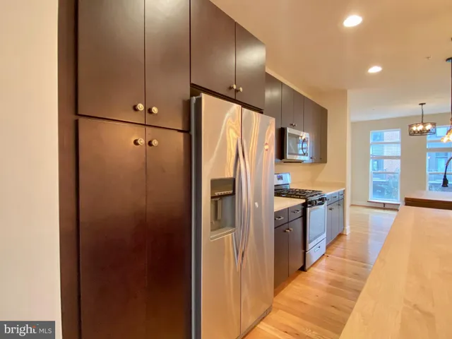 a large kitchen with stainless steel appliances a refrigerator and a stove top oven