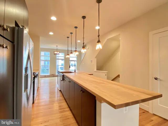 a large kitchen with kitchen island a sink stainless steel appliances and a chandelier
