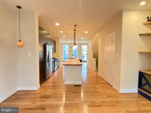 a view of a kitchen with kitchen island a counter top space appliances and a ceiling fan