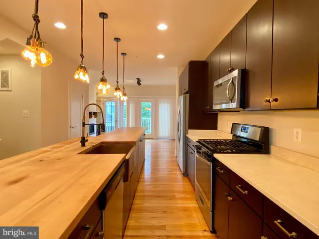 a kitchen with stainless steel appliances granite countertop a sink a stove and a wooden floors