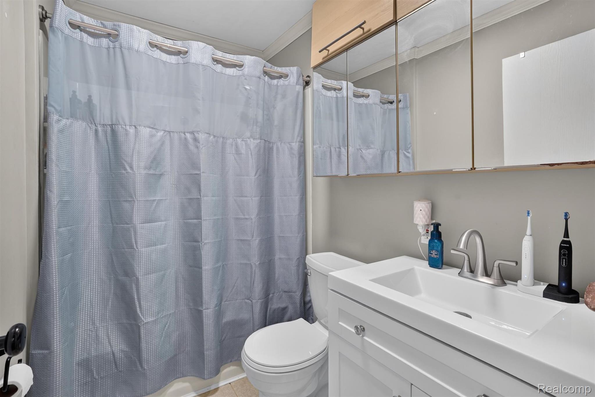 8696 West Sargent Road Fowlerville, MI 48836 - Photo 23 of 36 Bathroom featuring a white vanity with an integrated sink, brushed nickel faucet, and a wall-mounted mirrored medicine cabinet with overhead wood-finish cabinetry