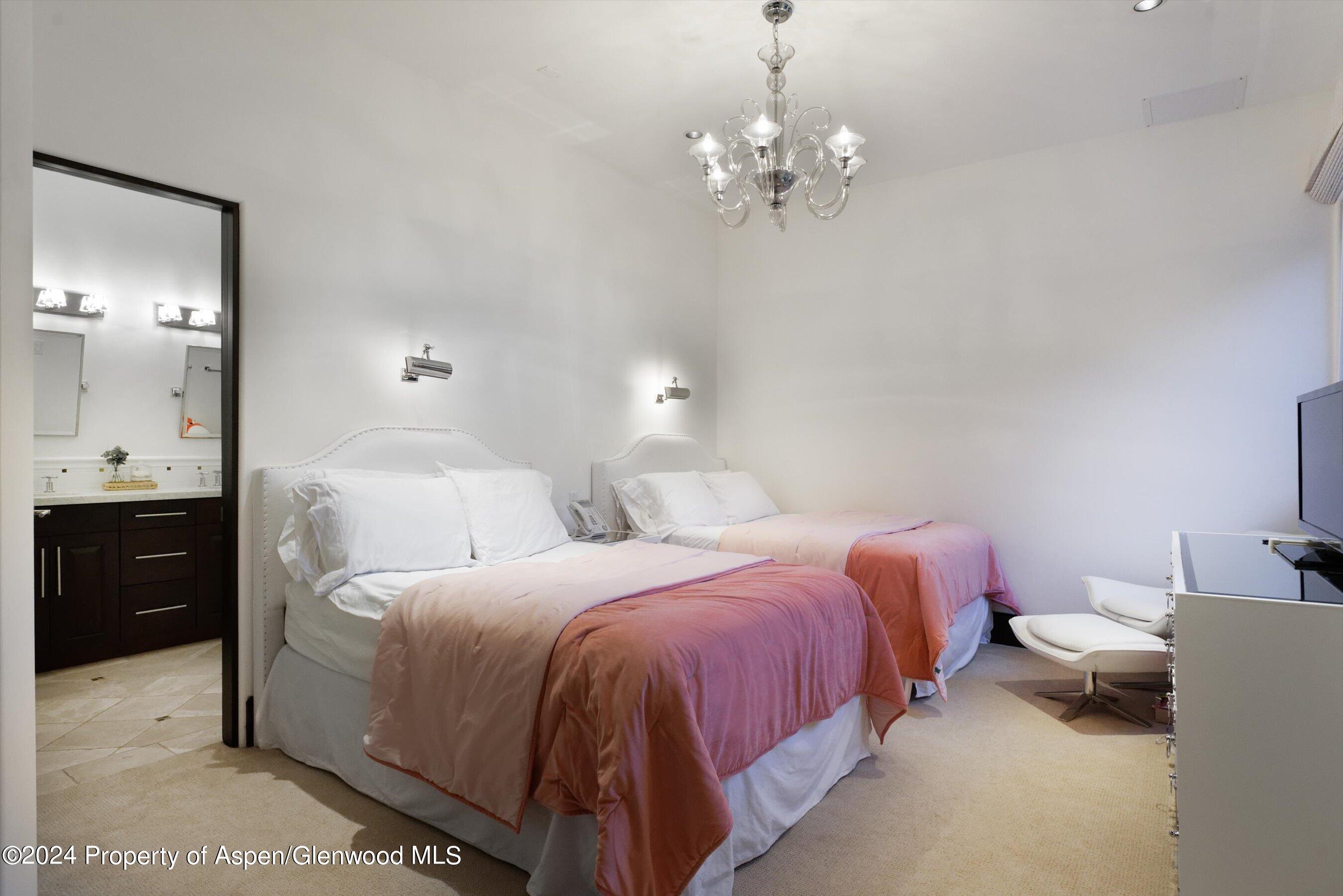 48 River Bend Road Snowmass, CO 81654 - Photo 21 of 32 a spacious bedroom with two beds and a chandelier