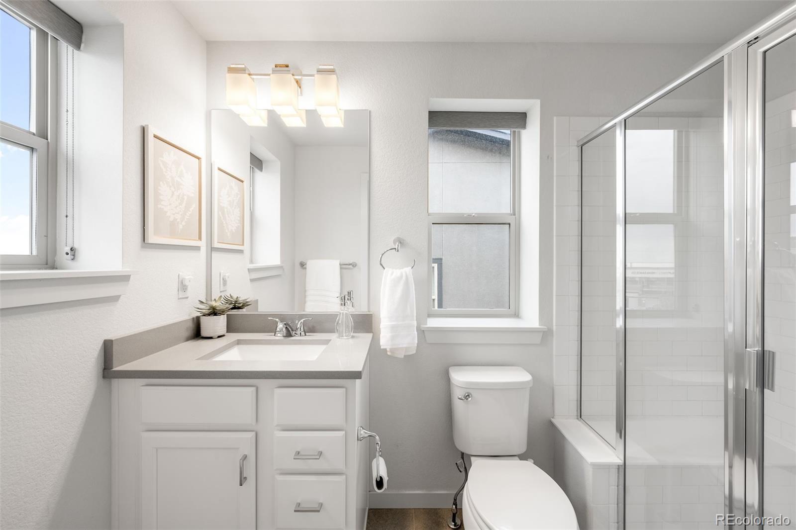 10053 Town Ridge Lane Lone Tree, CO 80124 - Photo 13 of 17 a bathroom with a toilet a sink a mirror a vanity and window