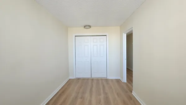a view of an empty room with closet and a window