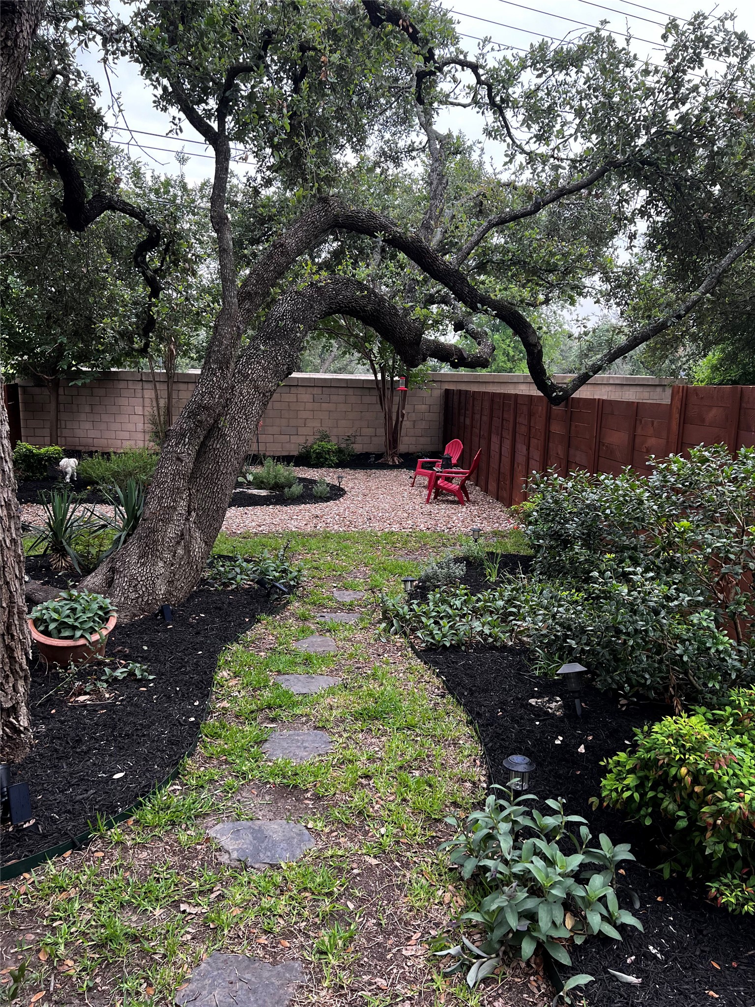 11000 Anderson Mill Road, Unit 93 Austin, TX 78750 - Photo 19 of 27 A flagstone path winds through a serene yard, framed by verdant plantings and mature trees.