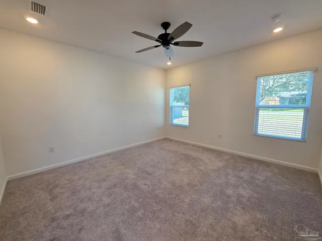 an empty room with windows and fan