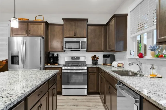 a kitchen with granite countertop a sink stove and refrigerator