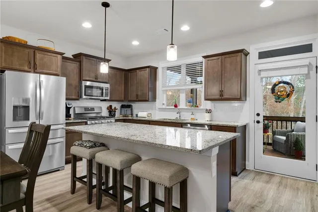 a large kitchen with kitchen island granite countertop a table chairs sink and refrigerator