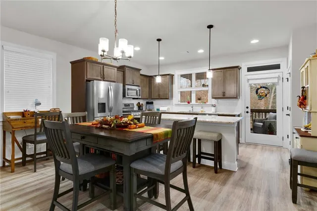 a kitchen with stainless steel appliances kitchen island granite countertop a dining table chairs and a refrigerator