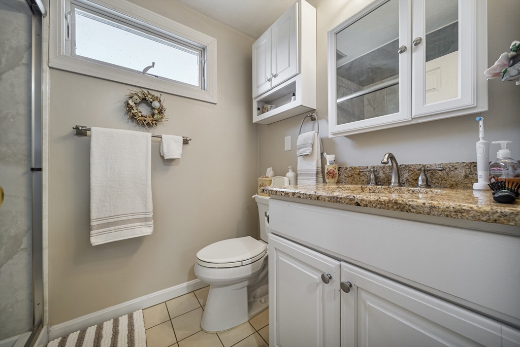 21 Tulip Circle, Unit 21 Haverhill, MA 01830 - Photo 17 of 26 a bathroom with a granite countertop sink a toilet and a shower curtain