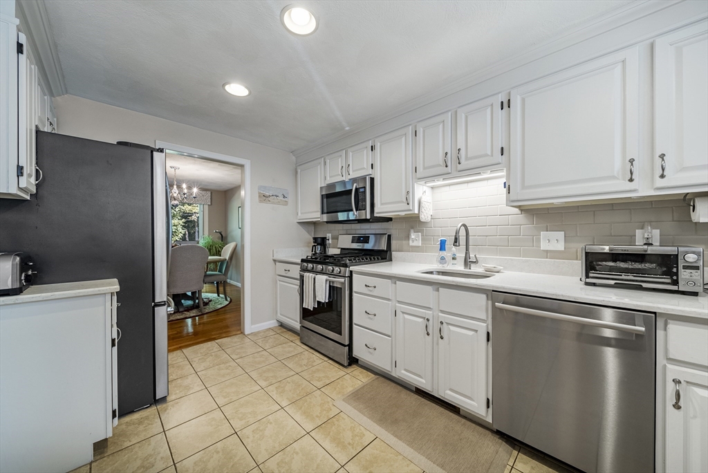 21 Tulip Circle, Unit 21 Haverhill, MA 01830 - Photo 5 of 26 a kitchen with granite countertop white cabinets and stainless steel appliances