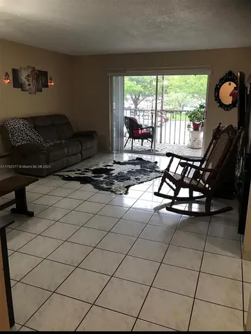 a living room with furniture a floor to ceiling window and a table in it