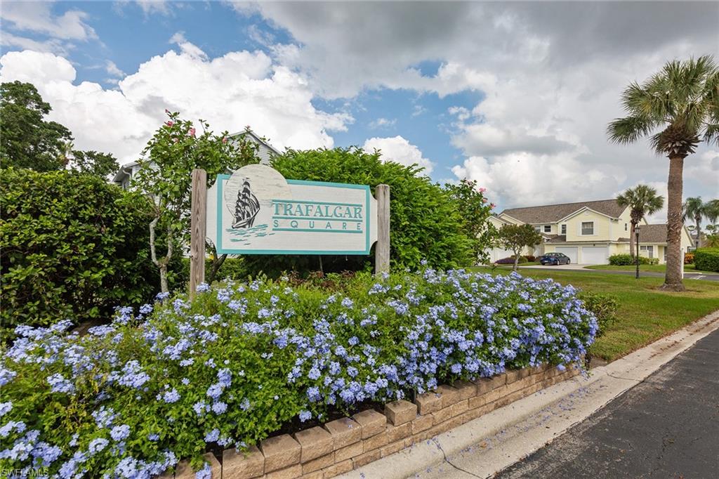 1535 Trafalgar Lane, Unit R201 Naples, FL 34116 - Photo 2 of 10 a sign that is sitting in front of flowers