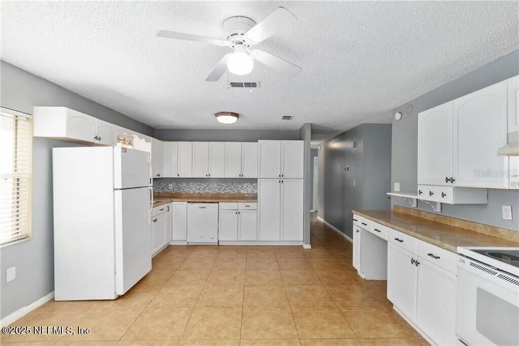 3991 Southeast 19th Avenue Ocala, FL 34480 - Photo 5 of 11 a kitchen with a refrigerator a sink and dishwasher with white cabinets